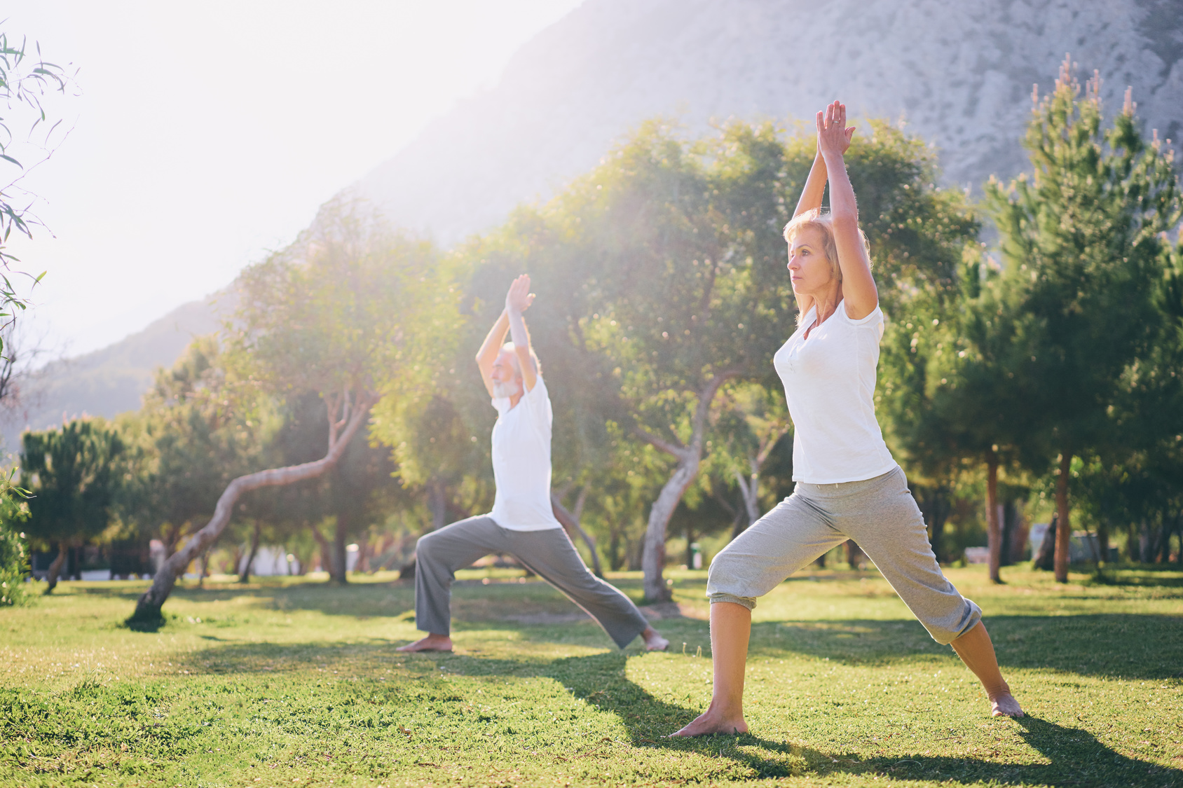 Yoga at park. Senior family couple exercising outdoors. Concept of healthy lifestyle.